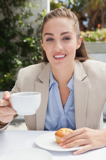 Mooie onderneemster die een koffie en een muffin heeft