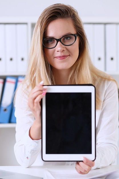 Mooie onderneemster die glazenportret dragen op het kantoor die een tablet houden