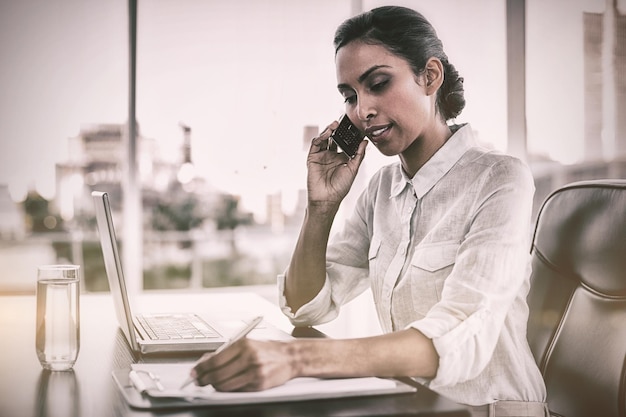 Mooie onderneemster werkende zitting bij haar bureau in het bureau