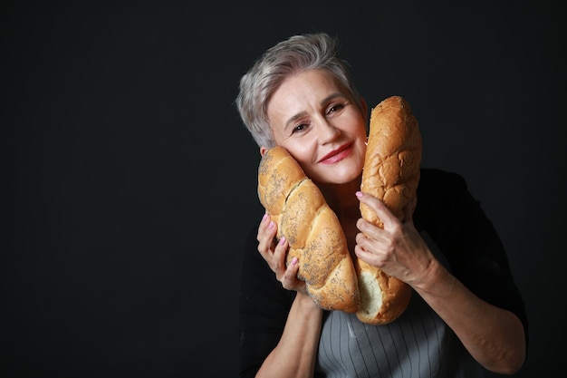 mooie oude vrouw in schort met brood in haar handen