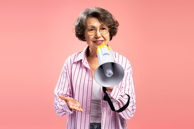 Mooie oudere vrouw in de jaren 70 met een bril en stijlvolle casual kleding met een megafoon