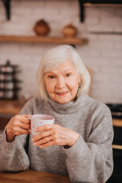 Mooie oudere vrouw in grijze trui ziet er goed uit