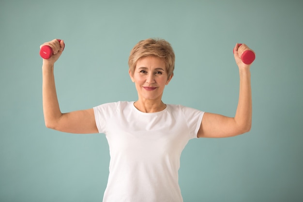 mooie oudere vrouw in wit T-shirt gaat sporten met halters