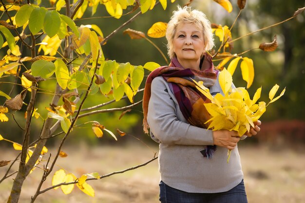 mooie oudere vrouw staat op een achtergrond van gele herfst