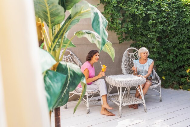 Mooie oudere vrouwen die thuis in de tuin ontspannen - Twee mooie volwassen dames rusten in een vredige achtertuin