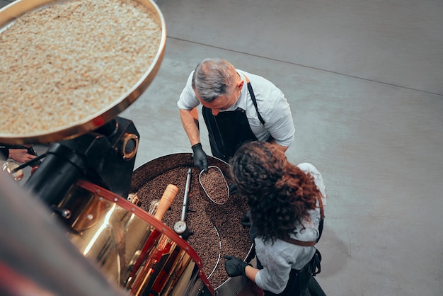 Mooie paar barista's controleren de kwaliteit van koffie uit de koffiebrander Bovenaanzicht?