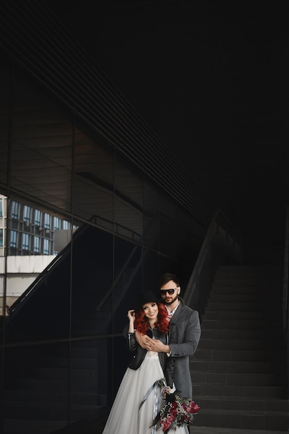 Foto mooie paar geliefden knuffelen buitenshuis tijdens bruiloft fotoshoot slanke jonge vrouw met rood haar...