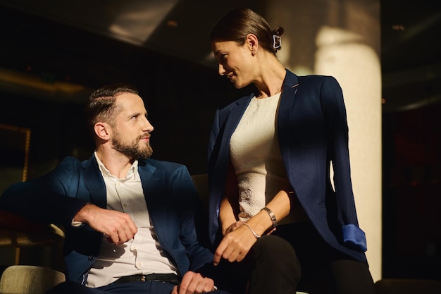 Mooie paar op huwelijksreis, collega's op zakenreis, vrouw en man, samen praten, communiceren, glimlachen, zittend op een fauteuil in de lounge zone van luxehotel