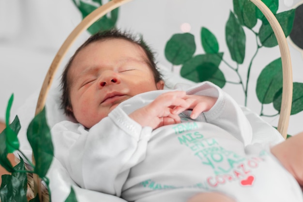 Mooie pasgeboren baby van 4 dagen oud slapend in een mand van bamboevezel en omgeven door groene bladeren