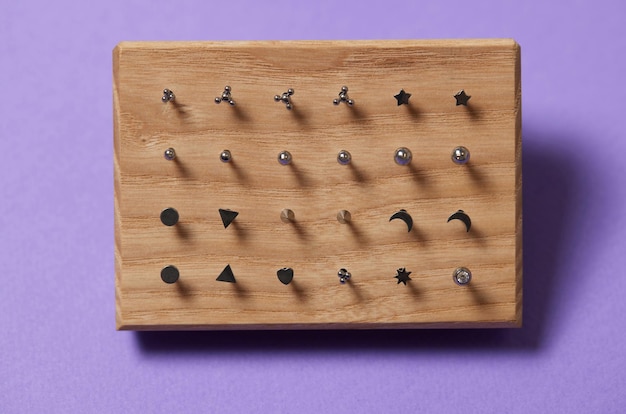 Mooie piercingsieraden op houten display Macro-opname Selectieve aandacht