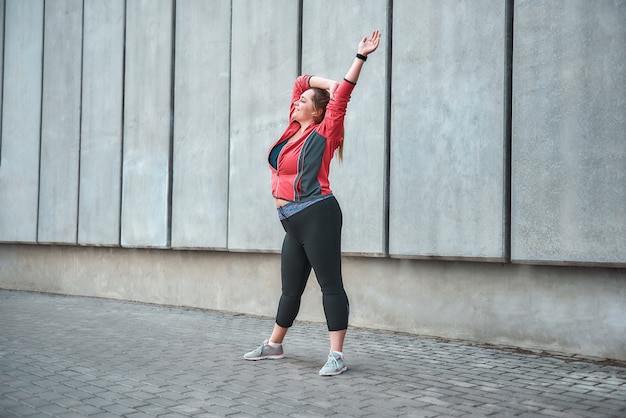 Mooie plus size vrouw in sportkleding die buiten sport en glimlacht