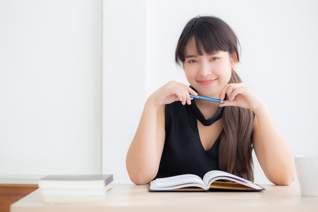 Mooie portret jonge aziatische vrouw het glimlachen zittingsstudie en het leren het schrijven notitieboekje