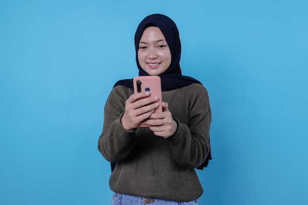 Mooie positief vriendelijk ogende jonge vrouw die hijab draagt met een mooie oprechte glimlach die zich dankbaar en dankbaar voelt met mobiele telefoon