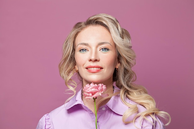 Foto mooie positieve vrouw met roze bloem op helderroze achtergrond