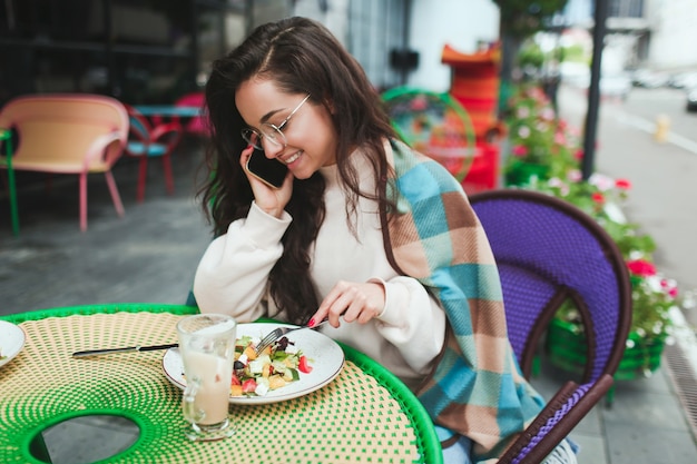 Mooie positieve vrouw praten over de telefoon tijdens de lunch