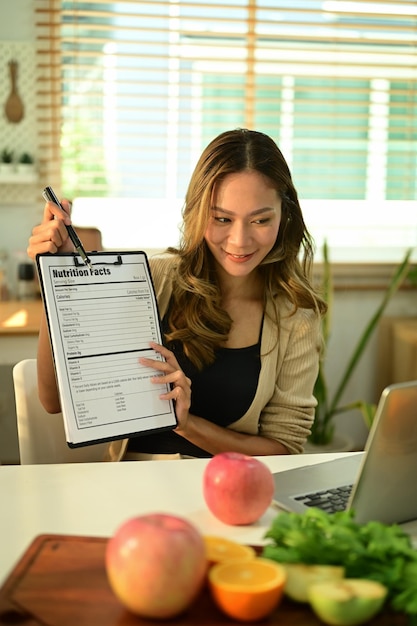 Mooie positieve vrouwelijke voedingsdeskundige biedt klant online consulten via laptop op kantoor