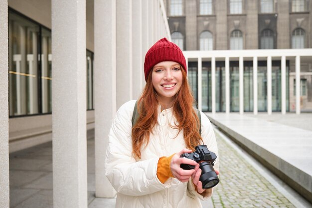 Mooie readhead girl fotograaf met professionele camera maakt foto's buiten rondlopen