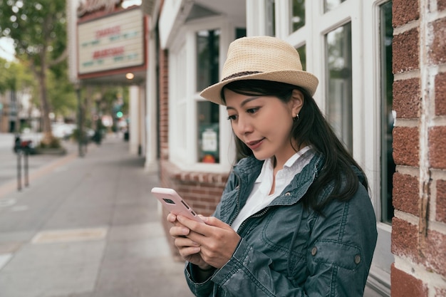 mooie reisvrouw die telefoon gebruikt om iets te zoeken terwijl ze op straat staat.