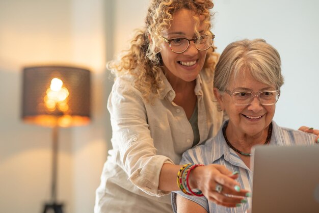 Mooie rijpe blonde vrouw die haar moeder leert hoe ze een laptop op internet moet gebruiken