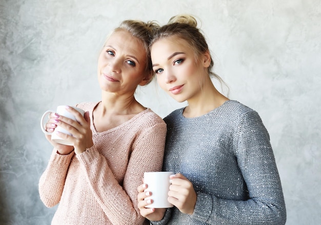 Mooie rijpe moeder en haar volwassen dochter drinken koffie