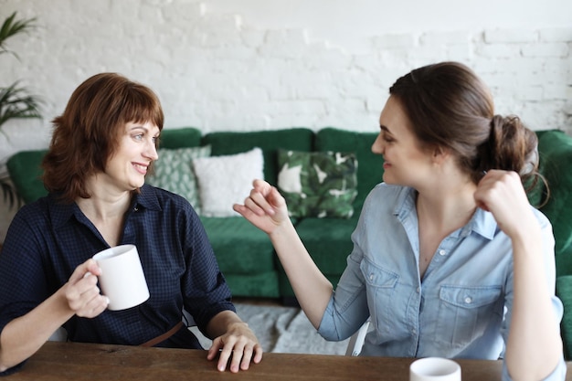 Mooie rijpe moeder en haar volwassen dochter drinken koffie