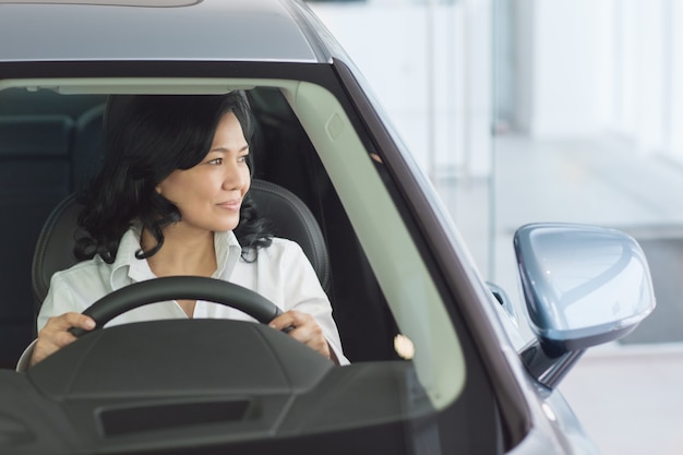 Foto mooie rijpe vrouw die nieuwe auto's controleert bij het dealership