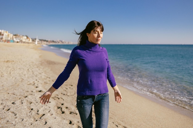 Mooie rijpe vrouw ontspannen ademen frisse lucht op een zonnige winterdag op het strand