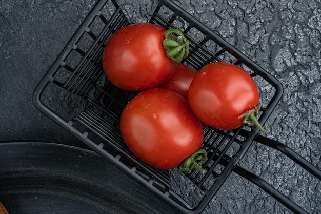 Foto mooie rode rijpe erfstuk verse tomaten op zwarte donkere stenen tafel achtergrond bovenaanzicht plat leggen
