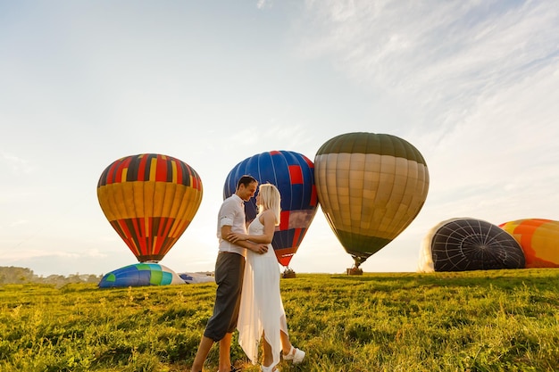 Mooie romantische paar knuffelen op weide. hete luchtballon op een achtergrond