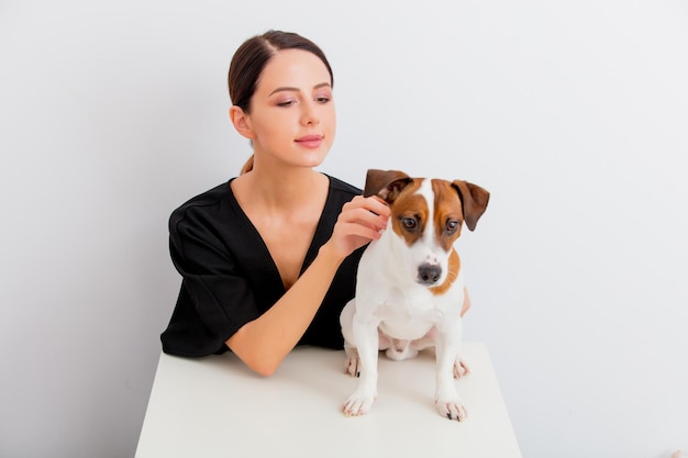 Mooie roodharige blanke vrouw in zwarte jurk met hond zittend aan witte tafel in lagom-stijl op witte achtergrond