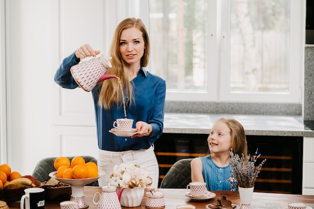 Mooie roodharige huisvrouw in blauw shirt en witte broek op keuken