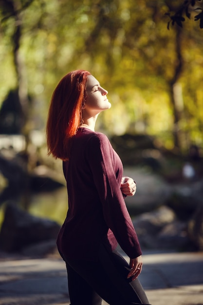 Mooie roodharige jonge vrouw loopt in het herfstpark. melancholische stemming