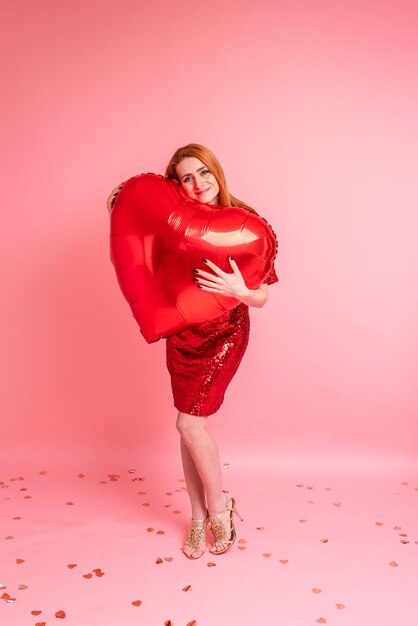 Mooie roodharige meisje met rood hart ballon poseren. Gelukkig Valentijnsdag concept