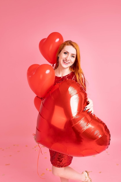 Mooie roodharige meisje met rood hart ballon poseren. Gelukkig Valentijnsdag concept