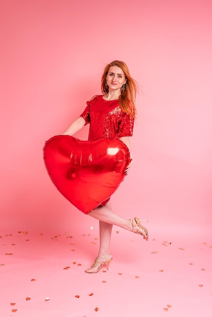 Mooie roodharige meisje met rood hart ballon poseren Happy Valentines Day concept