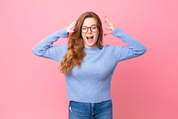 Mooie roodharige vrouw die schreeuwt met de handen in de lucht