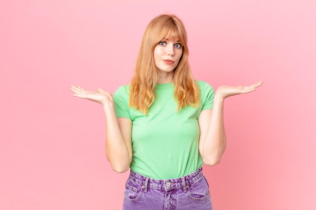 Foto mooie roodharige vrouw die zich verward en verward voelt en twijfelt