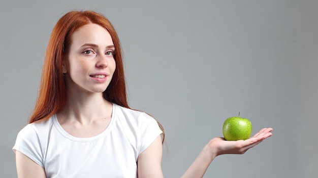 Mooie roodharige vrouw heeft een groene appel in haar handpalm