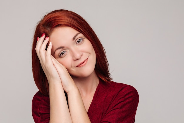 mooie roodharige vrouw houdt haar hoofd met haar handen