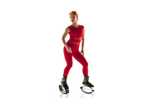 Mooie roodharige vrouw in een rode sportkleding springen in een kangoo