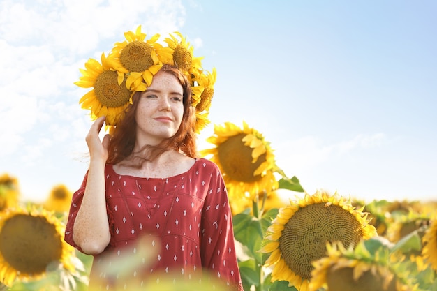 Mooie roodharige vrouw in zonnebloemveld op zonnige dag