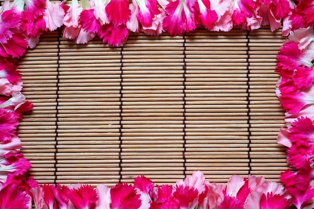 Mooie roze anjers bloemblaadjes bloemen frame op bamboe mat achtergrond. Valentijnsdag.