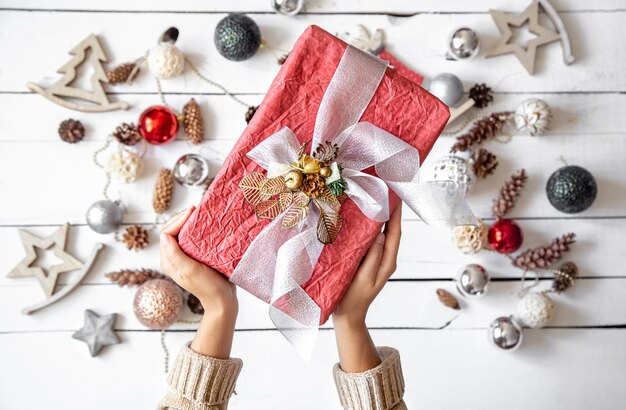 Mooie roze geschenkdoos in handen tegen de muur van details van kerstdecor close-up.