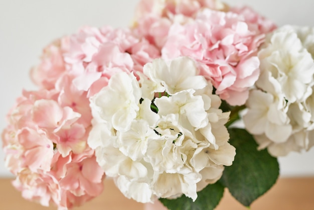 Mooie roze hortensia bloemen in vaas op tafel.