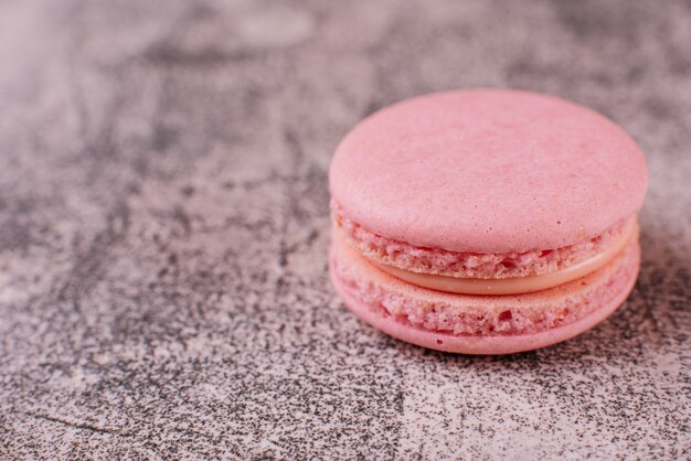 Mooie roze smakelijke bitterkoekjes op een concrete achtergrond