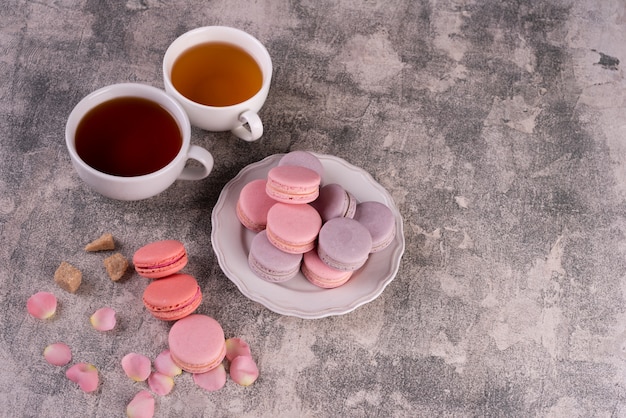 Mooie roze smakelijke bitterkoekjes op een concrete achtergrond