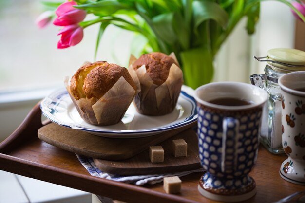 Mooie roze tulpen in een vaas met cupcakes en koekjes in de vintage keuken