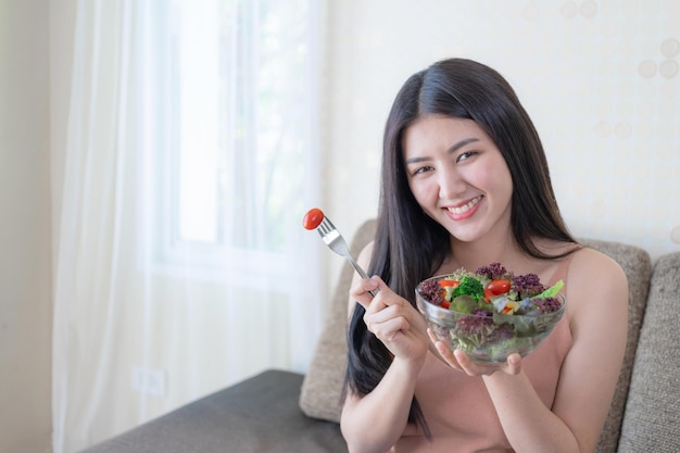 Mooie schoonheid vrouw Aziatisch schattig meisje voelt zich gelukkig eten dieet voedsel verse salade voor een goede gezondheid in de ochtend genieten van tijd in haar huis witte slaapkamer achtergrond levensstijl schoonheid vrouw concept