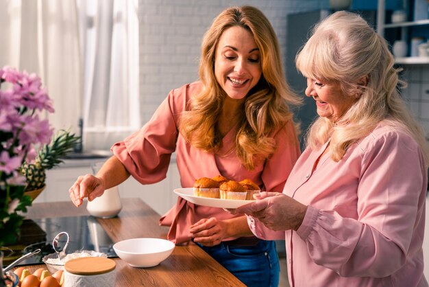 Mooie senior vrouw en dochter bakken in de keuken