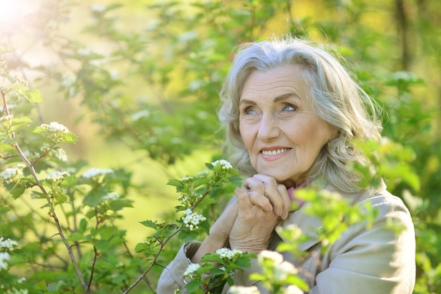 Mooie senior vrouw poseren in de buurt van bloeiende boom